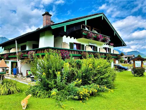 ein Haus mit Blumen und einem Hund davor in der Unterkunft Hotel - Pension Alpenstern in Schönau am Königssee