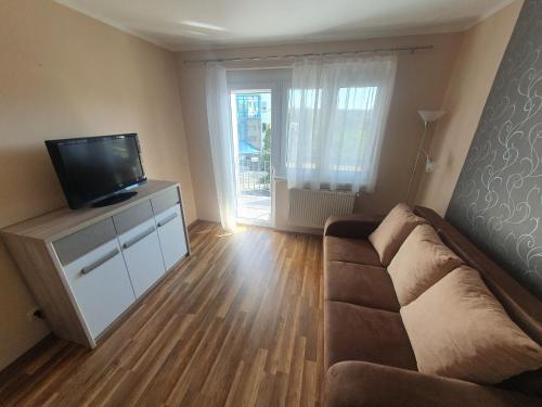 uma sala de estar com um sofá e uma televisão de ecrã plano em Csillagfény Apartment em Eger