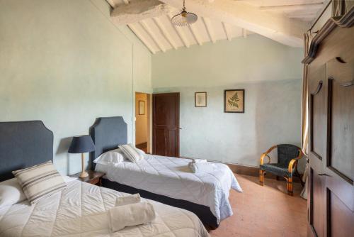 a hotel room with two beds and a chair at Castello di Bossi in Castelnuovo Berardenga