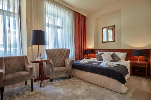 a hotel room with a bed and a chair and a mirror at Grand Hotel Stamary in Zakopane