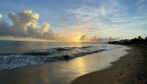 a beach with the sun setting in the distance at Cabarete Beachfront Condos at Nanny Estate C-5 in Cabarete