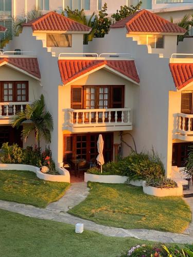 a house with red tile roofs and a yard at Cabarete Beachfront Condos at Nanny Estate C-5 in Cabarete