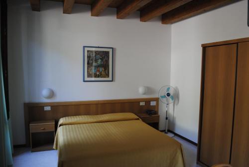 a bedroom with a bed and a white wall at Hotel Tiziana Garnì in Gargnano