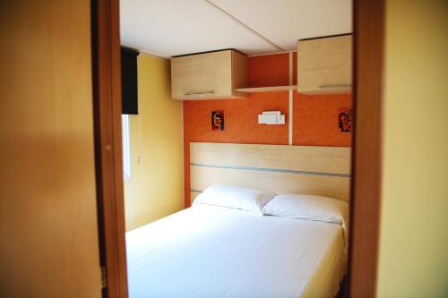 1 dormitorio pequeño con 1 cama con sábanas blancas en Camping Port Massaluca, en Pobla de Masaluca