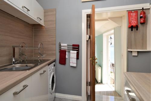 a kitchen with a sink and a washing machine at Arthur's Seat in Innellan