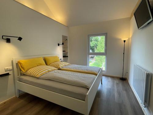 ein Schlafzimmer mit einem Bett mit gelben Kissen und einem Fenster in der Unterkunft Ferienwohnung Panorama Teichblick in Heldritt