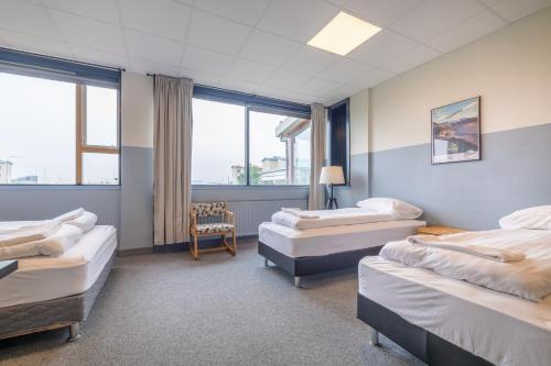 una habitación con 3 camas y una silla. en ABC Hotel by Reykjavik Keflavik Airport en Keflavík