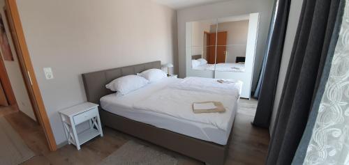 a bedroom with a bed with white sheets and a mirror at Outletcity Ferienwohnung Wohnung 2 in Metzingen