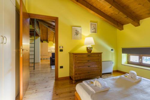 1 dormitorio con paredes amarillas, 1 cama y vestidor en Appartamento TOPAZIO, en Verona
