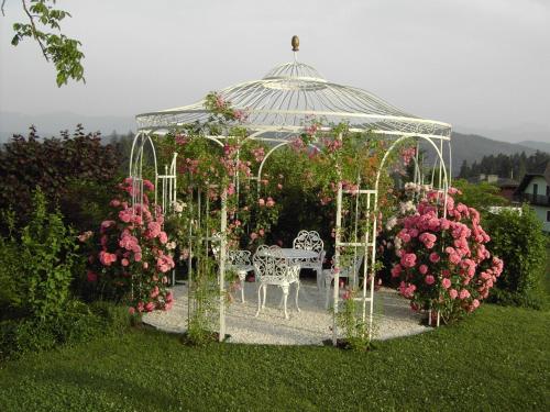 a gazebo with a bench and pink flowers at Ferienwohnungen Kremsbrucker in Klagenfurt