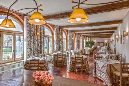 un restaurant avec des tables, des chaises et des fenêtres dans l'établissement Hotel Monasterio de Leyre, à Yesa