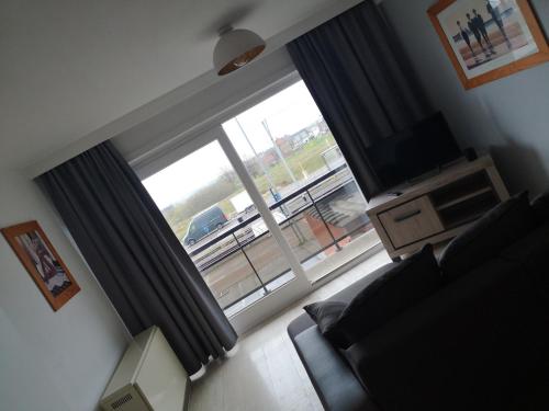 a living room with a large window and a television at Duinenzicht in Middelkerke