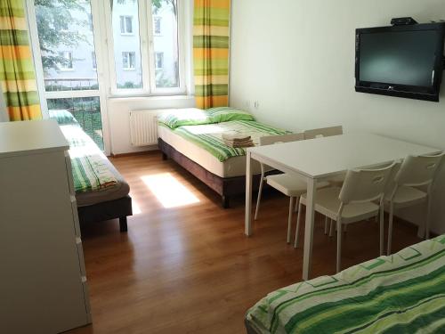 a room with a table and a bed and a tv at Apartamenty Asia Kraków in Krakow