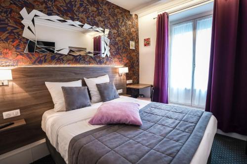 a bedroom with a bed with a pink pillow on it at Hotel De La TA in Rennes