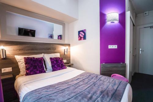 a hotel room with a large bed with purple walls at Hotel De La TA in Rennes
