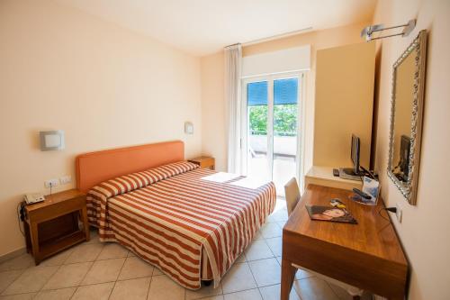 a bedroom with a bed and a desk and a television at Alba Hotel in Marina di Ravenna