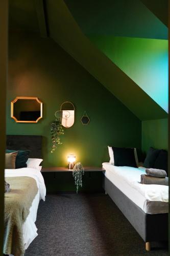 two beds in a room with a green wall at Timėjas in Ringaudai