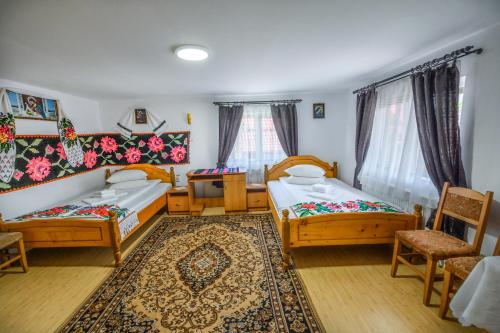 a room with two beds and a table and chairs at Pensiunea Poienita in Budeşti