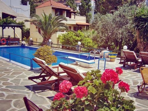 a swimming pool with chairs and flowers next to a house at Villa Rena in Batsi