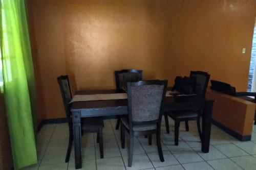 a dining room table with chairs and a piano at Unity Villa Near Montego Bay and Beaches free WiFi 2bedrooms in Montego Bay