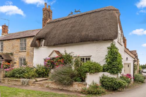 an old white cottage with a thatched roof at Rose Cottage in Evesham