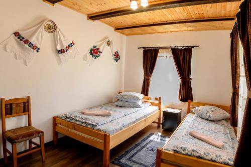 a bedroom with two beds and a chair at Casa Cupcea in Budeşti