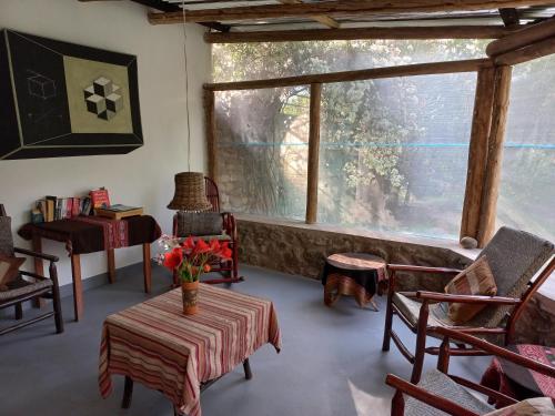 a living room with a table and chairs and a window at Andean Spirit Lodge in Mollepata