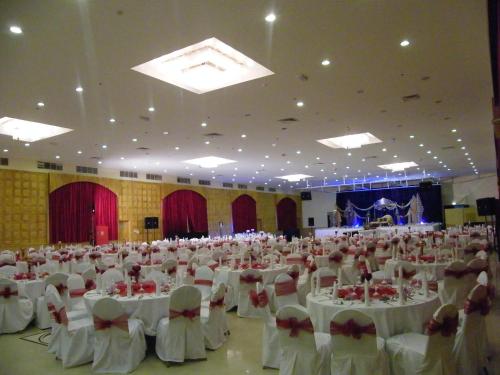 a large banquet hall with white tables and chairs at Ramee Dream Resort in Seeb