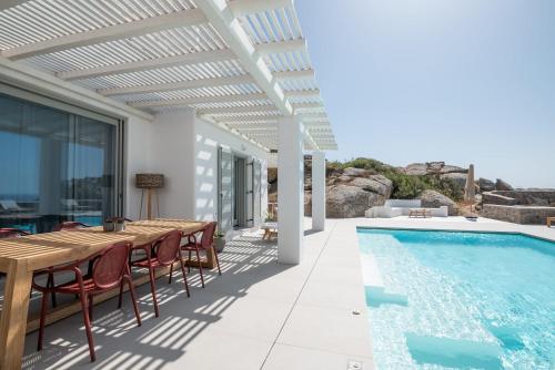 a patio with a table and chairs next to a swimming pool at Villa Petra Mare above Mykonos town Private pool in Mikonos