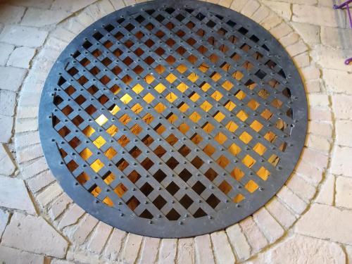 a metal manhole cover on a brick sidewalk at Monpoupon in Gropparello