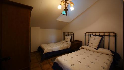 a bedroom with two beds and a window and a chandelier at Casa Rural Plaza Vieja Saldaña in Saldaña