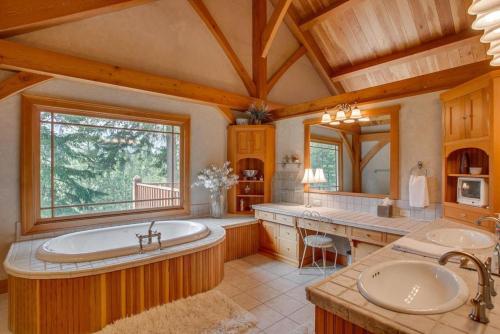 Snowgrass Lodge - River, Mountain Views & Hot tub في ليفنوورث: حمام كبير مع مغسلتين وحوض استحمام