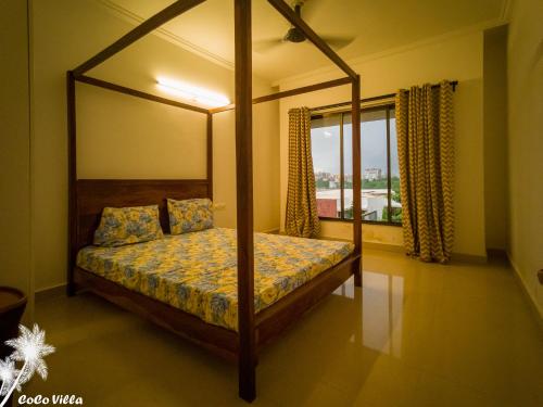 a bedroom with a canopy bed and a window at Cocó Villa - 3 BHK Private Sea View Villa with Garden in Sancoale