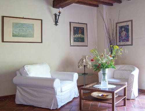 a living room with two chairs and a table with flowers at Torre Della Chiocciola in Monteriggioni