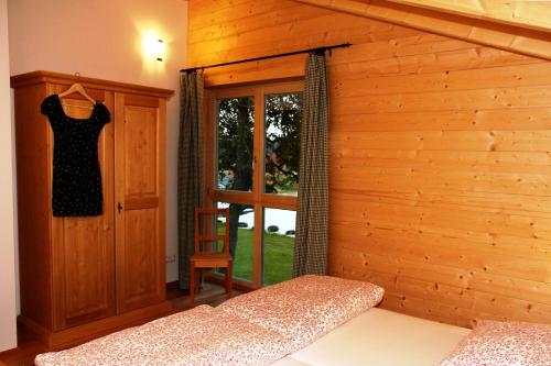 a bedroom with a wooden wall with a dress hanging on a door at Ferienhaus Eller in Traunwalchen