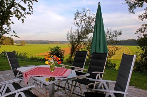 a patio with a table and chairs and a green umbrella at Ferienhaus Eller in Traunwalchen
