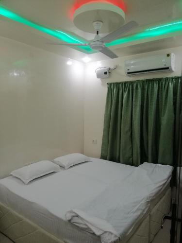 a bed in a room with a ceiling fan and green lights at RAJHAT MARANAO House in Bodh Gaya