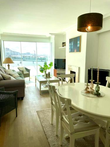 een woonkamer met een witte tafel en stoelen en een bank bij Westside Appartement met zicht op zee en het Rubensplein. Top Ligging! in Knokke-Heist