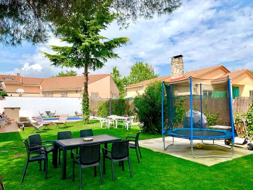 a backyard with a table and chairs and a trampoline at LaCasitadelaPraderapuntoes in Torremocha de Jarama