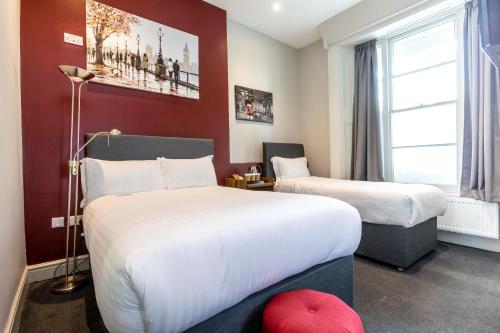 Una habitación de hotel con dos camas y una ventana. en Royal Park Hotel, en Londres