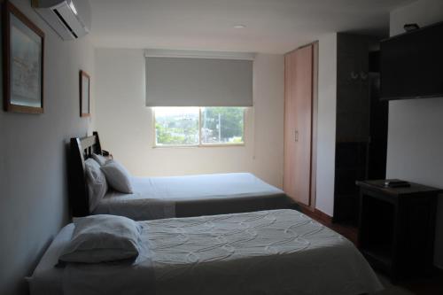 a bedroom with two beds and a window at Hotel Mar del Plata in Cartagena de Indias