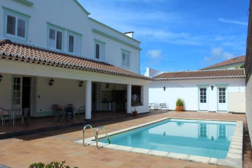 a villa with a swimming pool in front of a house at Bella Italia Populo Guest House in Ponta Delgada