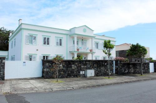 a large white house with a stone wall at Bella Italia Populo Guest House in Ponta Delgada