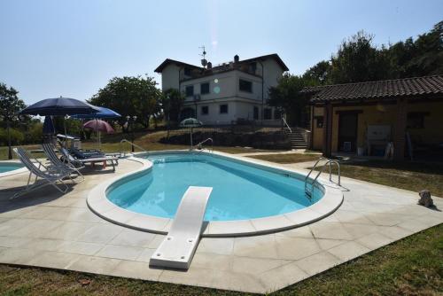 a large swimming pool with a house in the background at Cascina Rosa Camilla in Carpeneto