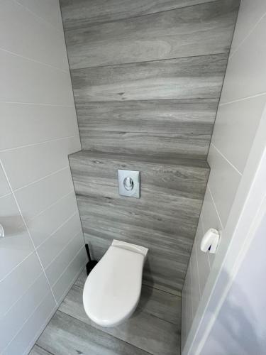 a white toilet in a bathroom with wooden walls at Domki Norda II in Władysławowo