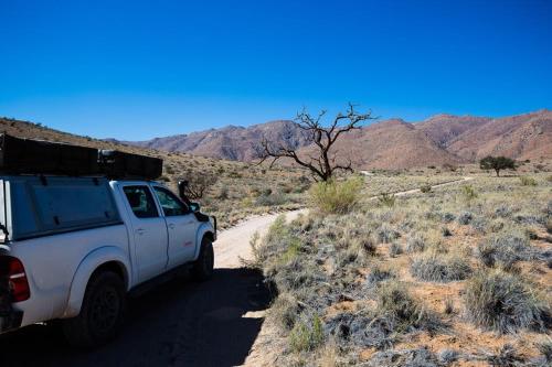 a white truck parked on a dirt road in the desert at Camp Gecko - PRIVATE NATURE RESERVE; TENTED CAMP AND CAMPSITE in Solitaire