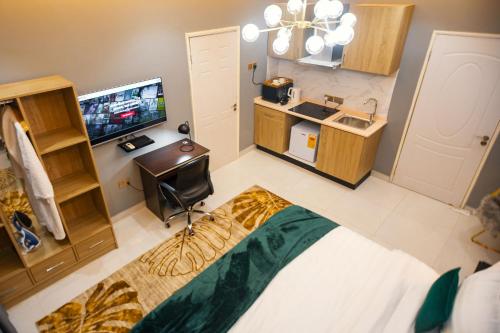 a room with a bed and a television in it at The Avery Suites, East Legon in Accra