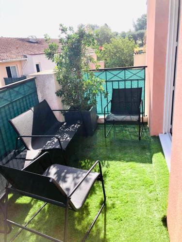 a balcony with two chairs and a bench on the grass at Les Jardins des Senteurs - Appartement privé avec piscine et parking in Grasse
