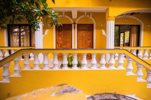 a yellow house with white railings on a balcony at Primavera Holiday Homes-FAMILY RUN GOAN GUEST HOUSE in Candolim