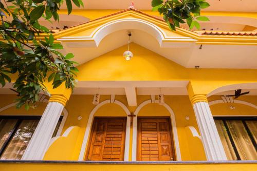 a yellow building with columns and a ceiling at Primavera Holiday Homes-FAMILY RUN GOAN GUEST HOUSE in Candolim